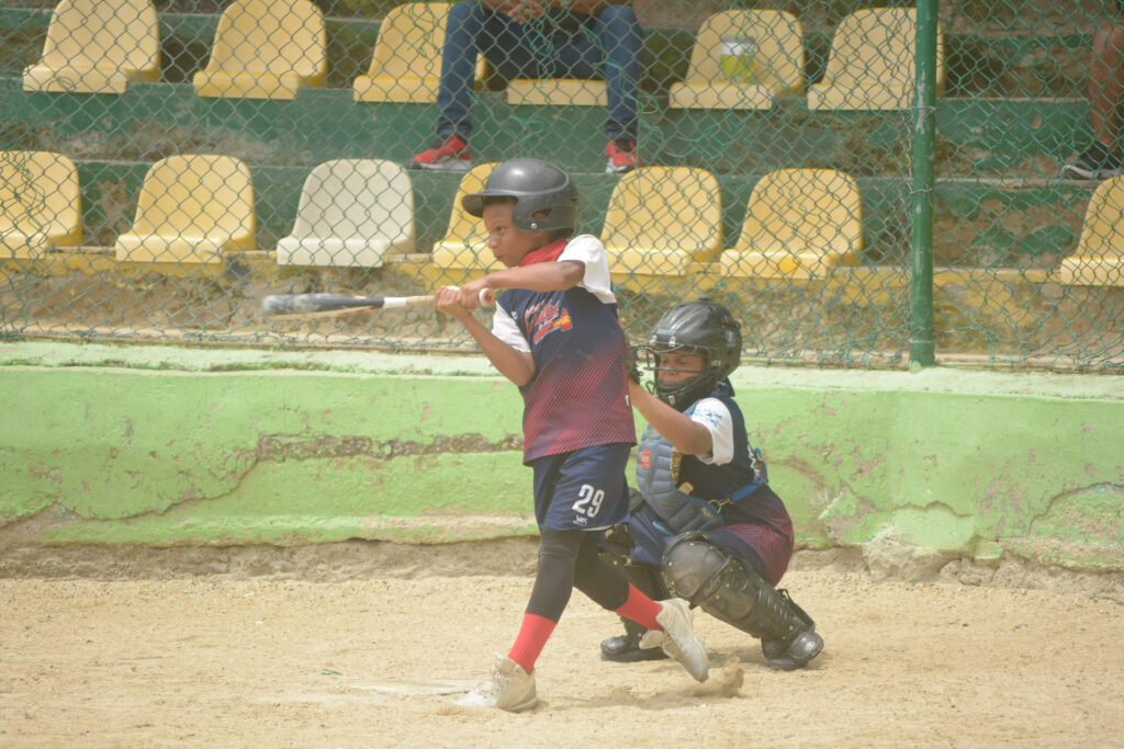 Child swinging bat in baseball game with the umpire behind him